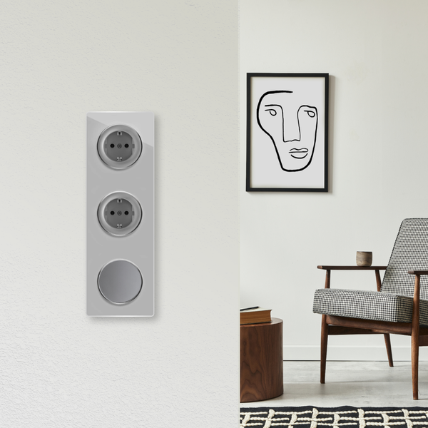 Moderne Wandsteckdosenkombination mit Schalter in einem Wohnraum mit Sessel und abstraktem Bild an der Wand.