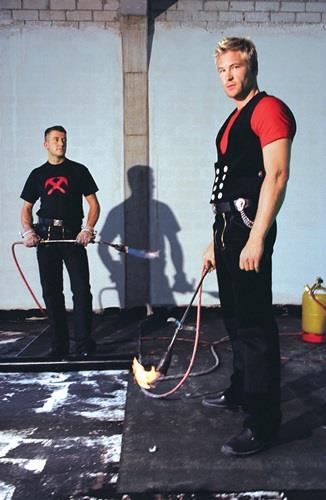 Zwei Dachdecker bei der Bitumenabdichtung mit einem Schweißbrenner auf einem Dach.