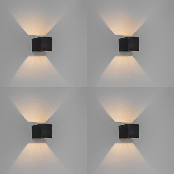 Vier schwarze, würfelförmige Wandleuchten strahlen Licht nach oben und unten.