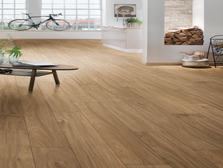 Ein heller, geräumiger Wohnraum mit Eichenholz-Laminatboden, einem Couchtisch, einer Küchenzeile und einem Kamin mit Holzstapel.