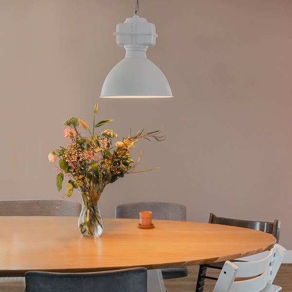Esstisch mit Blumenstrauß unter einer Hängelampe