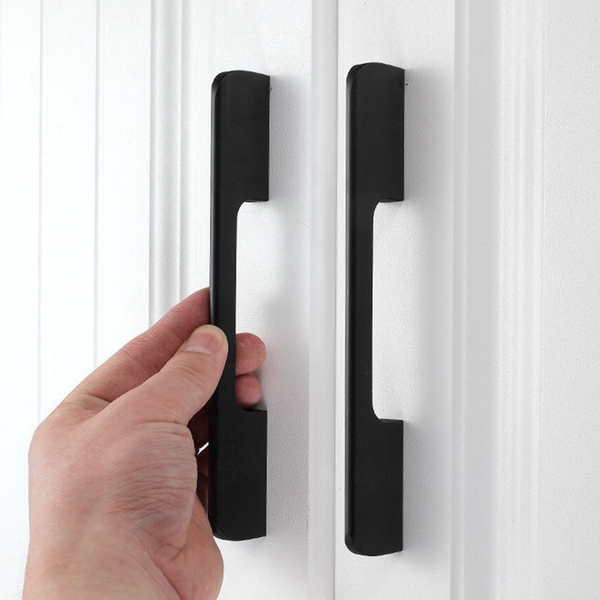 Eine Hand öffnet einen Schrank mit einem länglichen Griff.