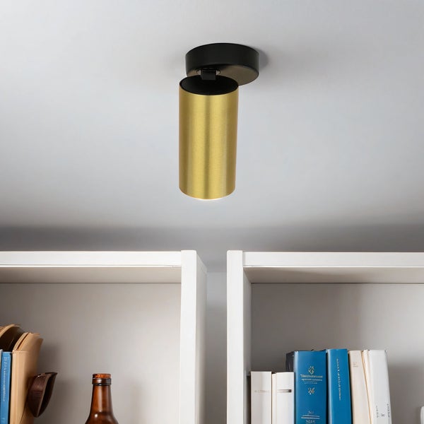 Goldfarbene Deckenleuchte aus Metall über einem Bücherregal