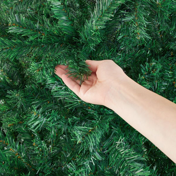 Künstlicher Weihnachtsbaum mit Hand, die einen Zweig berührt