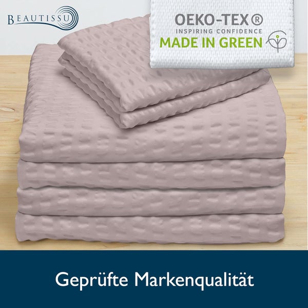 Gefalteter rosa Stoff mit Waffelstruktur, Oeko-Tex Made in Green Siegel für nachhaltige Textilien, Beautissu Logo und geprüfte Markenqualität.