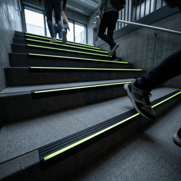 Menschen gehen eine Betontreppe mit nachleuchtenden Antirutsch Treppenkantenprofilen hinauf