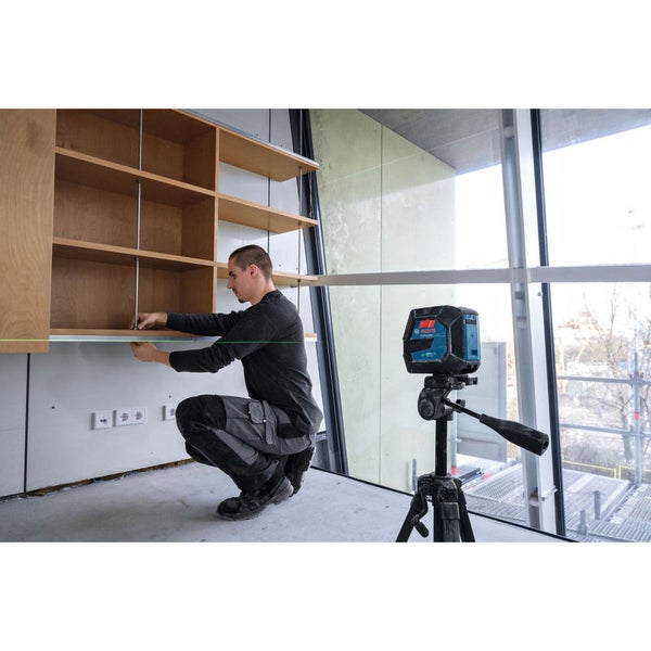 Ein Mann justiert ein Regal mit Hilfe eines Linienlasers auf einem Stativ.