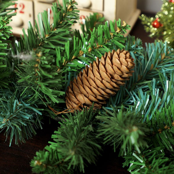 Künstliche Tannenzweige mit einem echten Kiefernzapfen als weihnachtliche Dekoration.