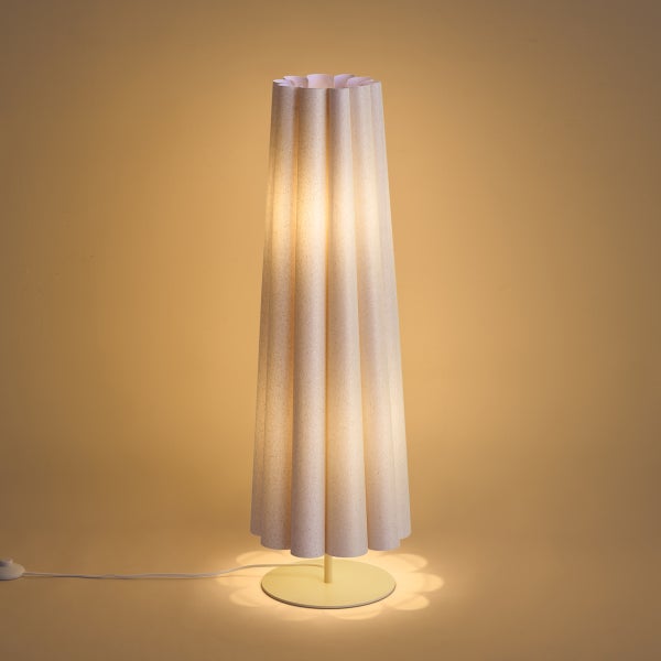 Moderne Stehlampe mit gefaltetem, säulenförmigem Schirm und rundem Standfuß, warm leuchtend.