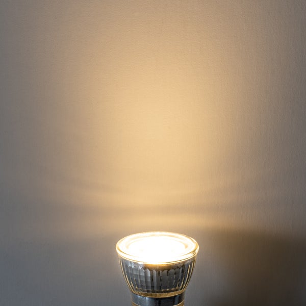 Eingeschaltetes LED-Reflektorleuchtmittel mit warmweißem Lichtstrahl an einer Wand.