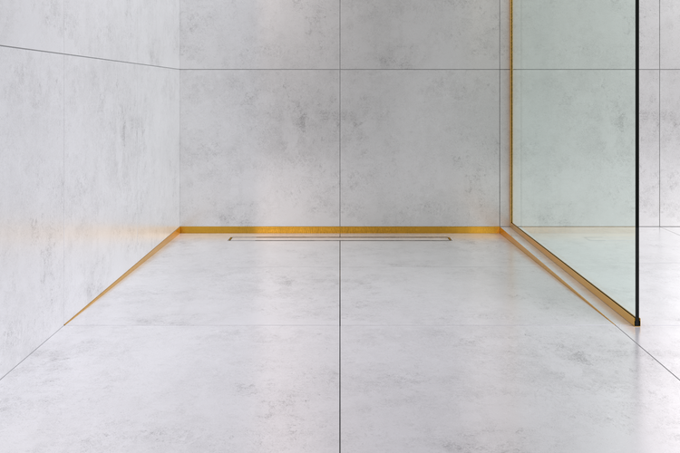 Bodengleiche Dusche mit hellgrauen Fliesen in Betonoptik, goldfarbenen Profilen, einer Duschrinne und einer Glasabtrennung.