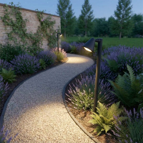 Moderne schwarze Wegeleuchten beleuchten einen Kiesweg in einem Garten mit Lavendel und einer Steinmauer bei Dämmerung.