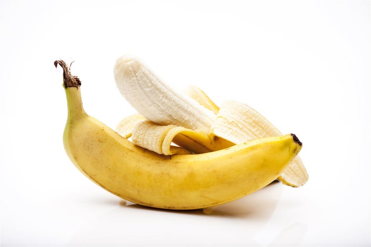 Eine halb geschälte Banane auf weißem Hintergrund.