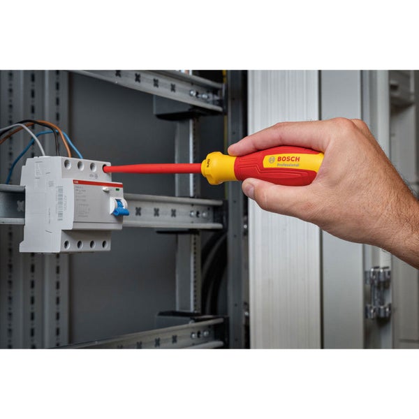 Elektriker verwendet einen isolierten Schraubendreher von Bosch an einer elektrischen Anlage.