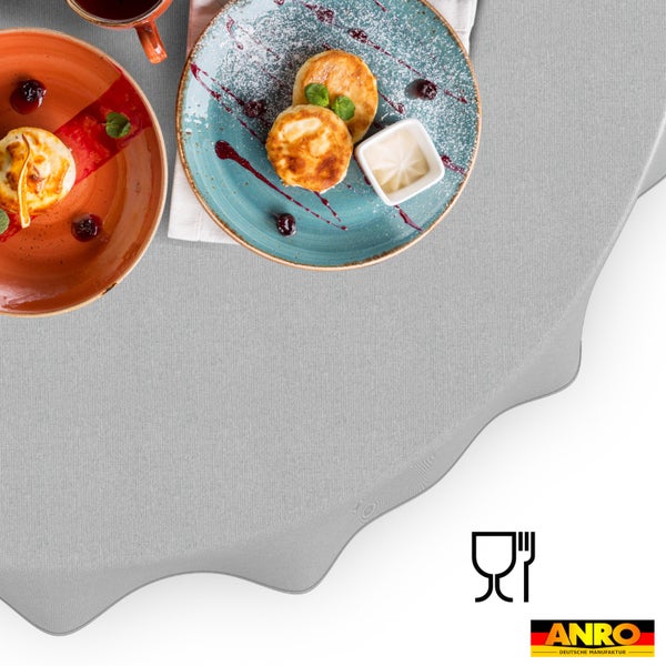 Tischdecke mit feiner Struktur auf einem gedeckten Tisch mit Desserttellern und einer Tasse. Lebensmittelecht. ANRO Deutsche Manufaktur Logo.