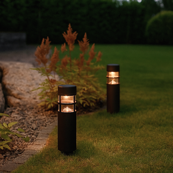Zwei leuchtende Wegeleuchten im Garten bei Dämmerung.