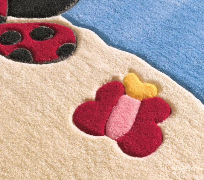 Nahaufnahme eines Kinderteppichs mit Schmetterlings- und Marienkäfer-Motiven aus weichem, strukturiertem Material.
