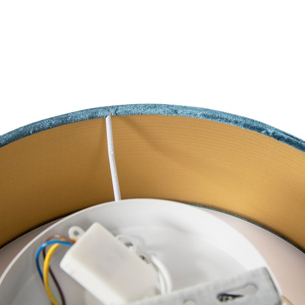 Nahaufnahme der Innenseite eines Lampenschirms mit goldfarbenem Futter, blauem Samt am Rand und weißem Montagesockel mit Verkabelung.