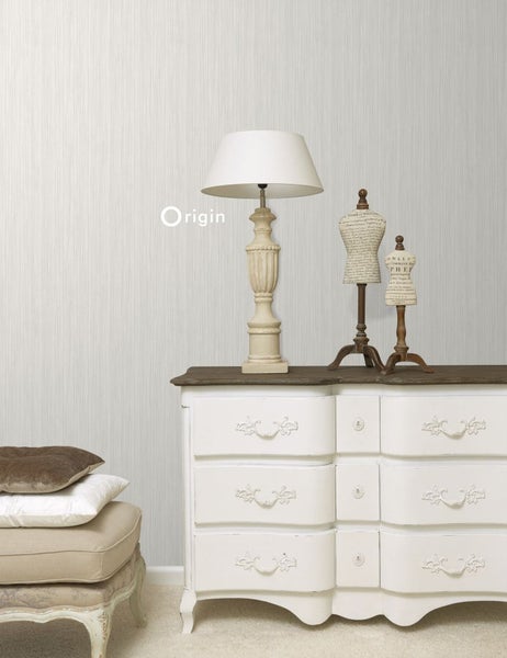 Heller Raum mit Kommode, Lampe, Dekorationspuppen und einem Stapel Kissen