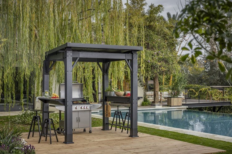 Grillpavillon mit Grill, Arbeitsfläche und Hockern neben einem Schwimmbad im Garten.