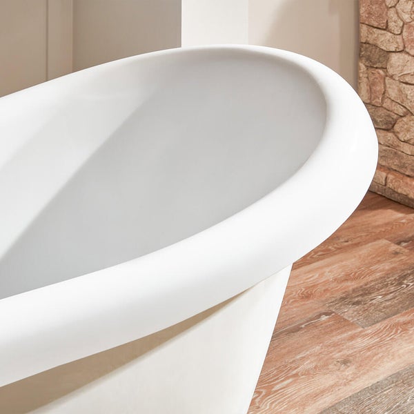Freistehende Badewanne mit ovalem Rand im Badezimmer mit Steinwand und Holzboden.
