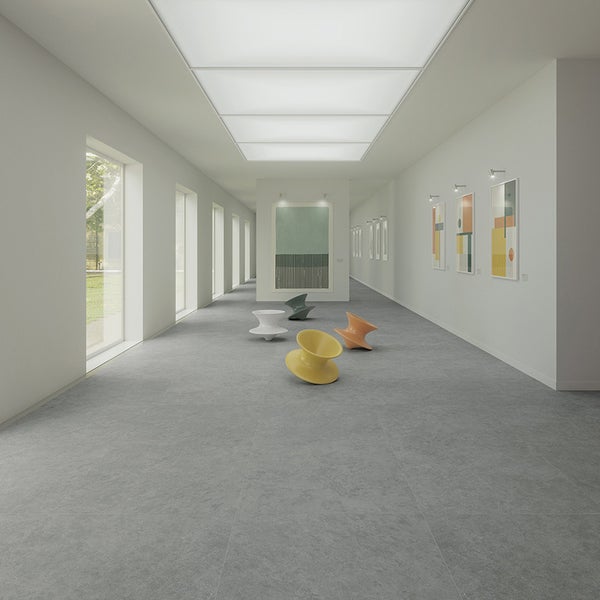 Heller Flur in einer Galerie mit großformatigen Steinfliesen auf dem Boden und moderner Sitzgelegenheit.