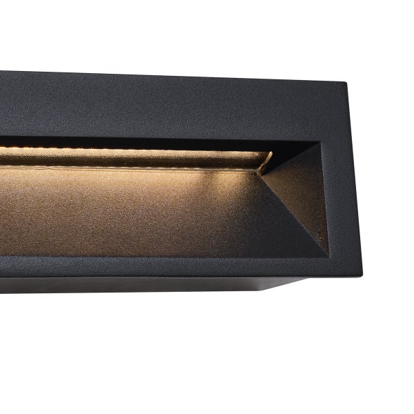 Rechteckige Außenwandleuchte in Schwarz mit warmweißem Lichtaustritt und strukturierter Oberfläche.