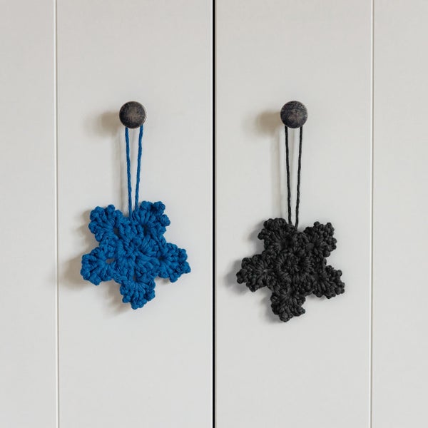 Blaue und schwarze sternförmige Dekohänger aus Strickmaterial an Möbelknöpfen.