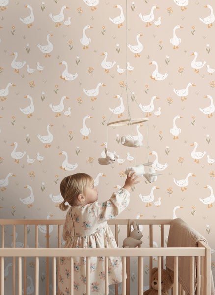 Tapete im Kinderzimmer mit Gänse- und Blumenmuster, im Hintergrund eines Kindes in einem Gitterbett aus Holz.