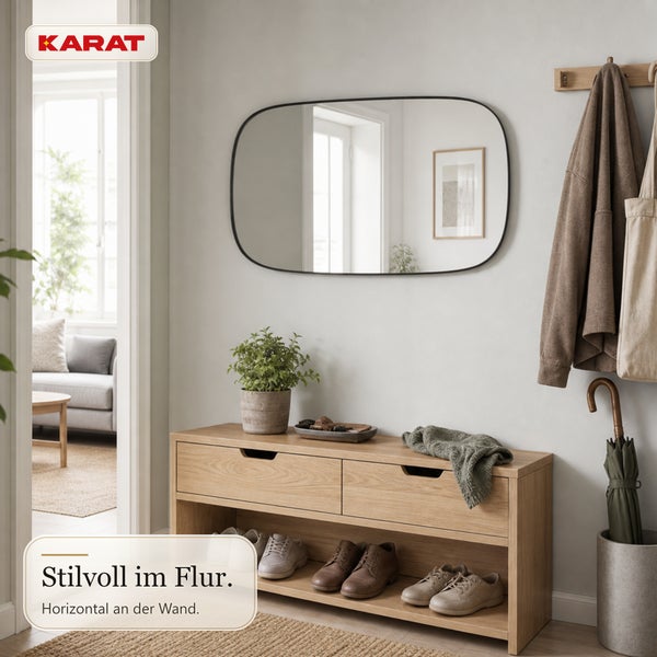 Ein moderner Flur mit Holzschuhbank, horizontalem ovalem Spiegel an der Wand und Karat Logo in einer hellen, aufgeräumten Wohnumgebung.
