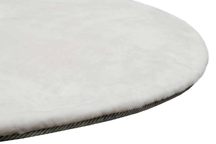 Nahaufnahme eines runden Kunstfellteppichs mit sichtbarer Rückseite und weicher Oberfläche.