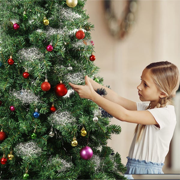 Ein Mädchen schmückt einen Weihnachtsbaum mit Christbaumkugeln und Lametta.