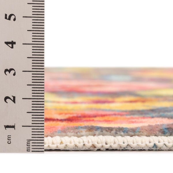 Nahaufnahme eines bunten Teppichs neben einem Lineal zur Messung der Florhöhe von circa 1 Zentimeter.