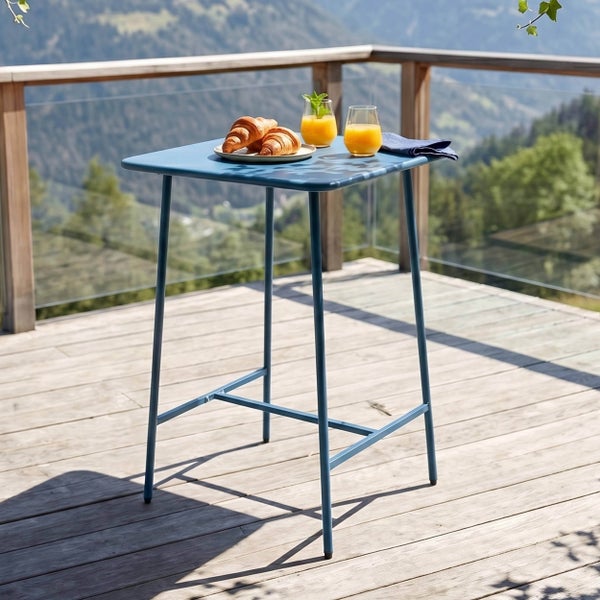 Quadratischer Stehtisch aus Metall auf einer hellen Holzterrasse mit Bergpanorama, gedeckt mit Frühstück.