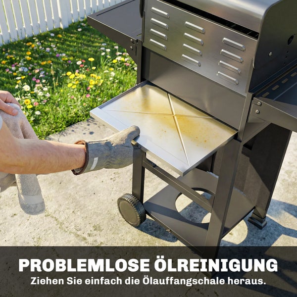 Eine Person zieht mit einem Hitzeschutzhandschuh die Ölauffangschale aus einem Grill zur einfachen Reinigung heraus.