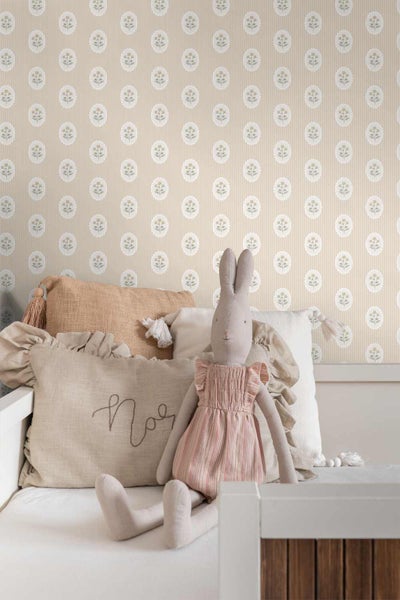 Vliestapete mit Blumen-Medaillons und Streifenmuster in einem hellen Kinderzimmer mit Bett, Kissen und Stoffhase.