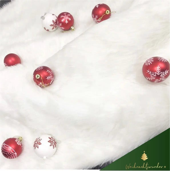 Weihnachtsdekoration mit Christbaumkugeln auf einem weißen Teppich