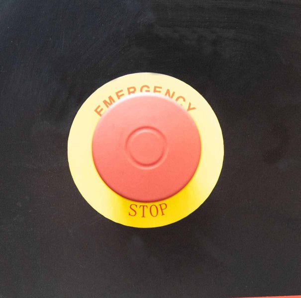 Roter Not-Halt-Taster mit gelbem Ring und der Aufschrift Emergency Stop