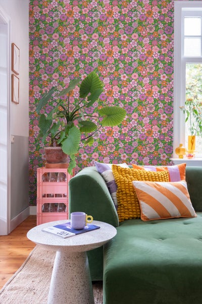 Wohnzimmer mit grüner Couch, Couchtisch und Tapete mit Blumenmuster