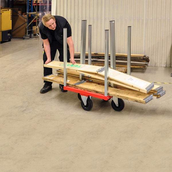 Mann belädt Transportwagen mit Holzplatten im Lager.