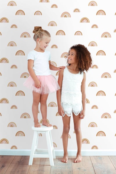 Zwei Mädchen vor einer Wand mit Regenbogenmuster
