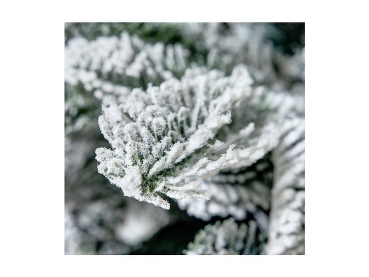 Nahaufnahme eines künstlichen Tannenzweigs mit Schnee-Effekt für die Weihnachtsdekoration.