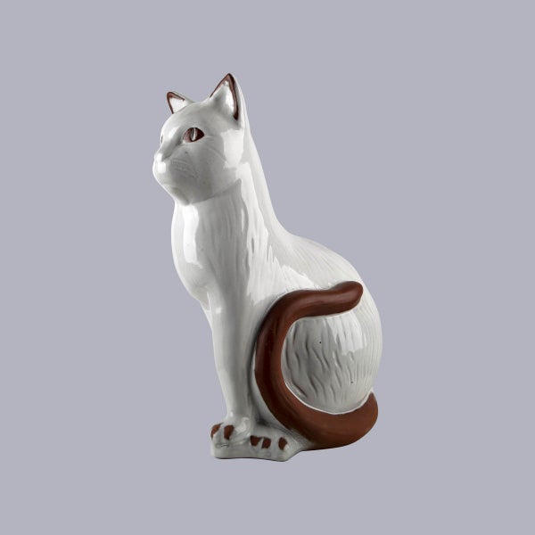 Sitzende Katzenfigur aus weiß-braun glänzender Keramik.