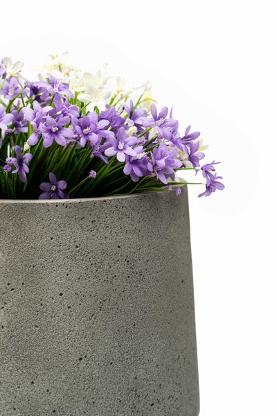 Blumentopf in Betonoptik mit lila und weißen Kunstblumen.