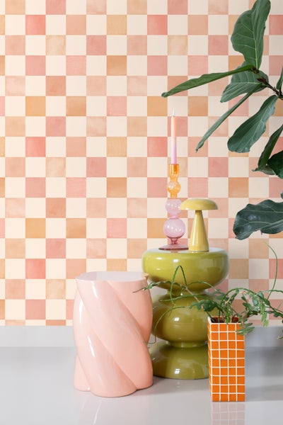 Szene mit Schachbrettmuster-Tapete, Zierpflanzen und Dekorationsgegenständen auf einem Tisch
