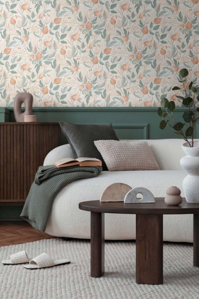 Wohnzimmer mit Vliestapete mit Blumenmuster, weißem Sofa, dunklem Couchtisch und Holzkommode in modernem Einrichtungsstil.