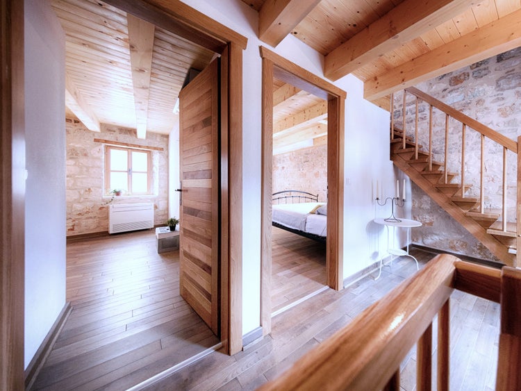Heller Innenraum mit Holzdielen, Sichtbalkendecke, massiven Innentüren, einer Holztreppe und Wänden aus Naturstein.