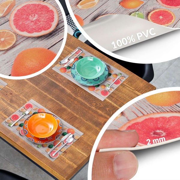 Tischset aus 100 Prozent Polyvinylchlorid mit Zitrusfrucht-Druck, 2 Millimeter dick, auf einem Holztisch mit Tellern und Besteck.