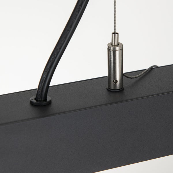 Detailansicht einer Hängeleuchte mit Kabel und Metallseilaufhängung an einem mattem Leuchtengehäuse.