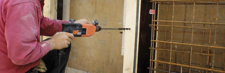 Bohrhammer Spit 322 im Einsatz beim Bohren in eine Holzschalung auf einer Baustelle.